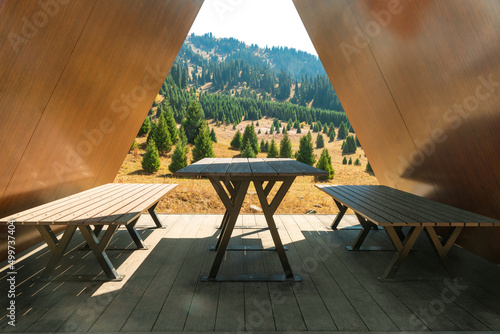 Fotografiet A table with benches under the gable roof of a gazebo in nature for tourists to