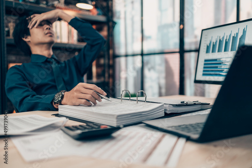 Serious Investors have a headache hold pen  working  on the desk.  Accounting and  Financial concept.