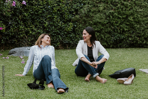 Latin business women sitting on grass and having fun at terrace office in Mexico Latin America	