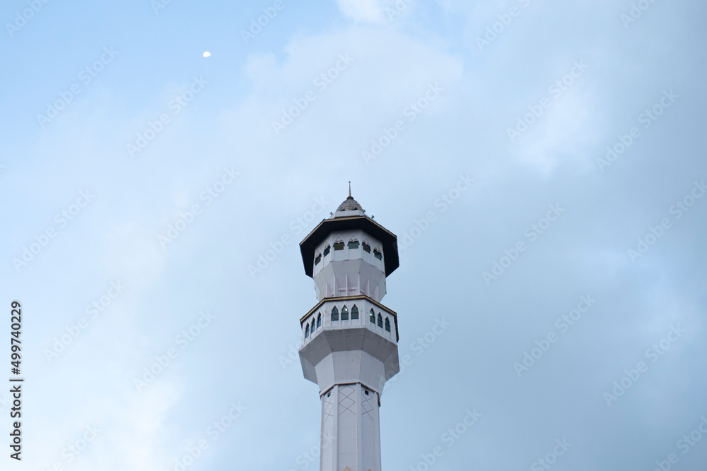 The minaret of the mosque and the moon in the afternoon
