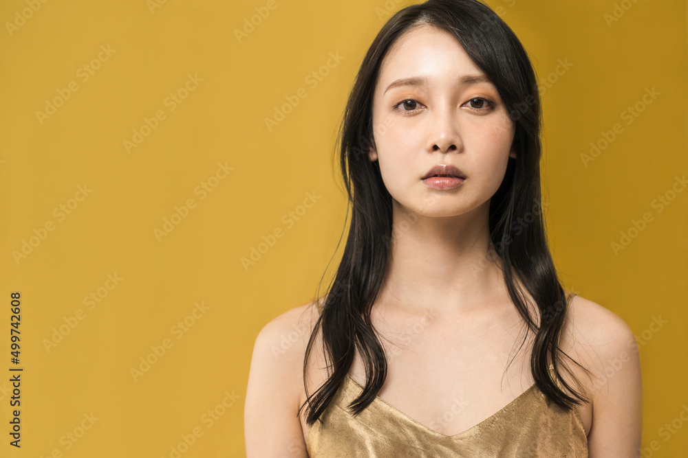 Black-haired woman standing in front of a golden background Black-haired woman standing in front of a golden background