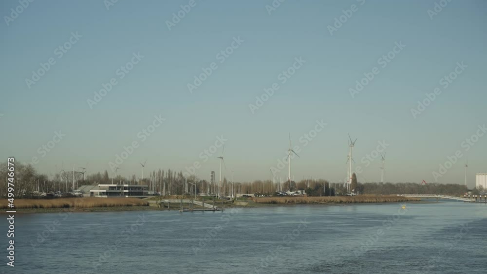 European river with green energy wind turbines in distance slow motion 4k 30p European river with green energy wind turbines in distance slow motion 4k 30p