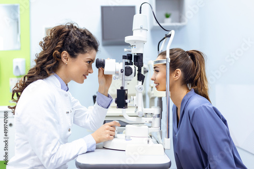 Eye doctor with female patient during an examination in modern clinic. Ophthalmologist is using special medical equipment for eye health saving and improving. photo