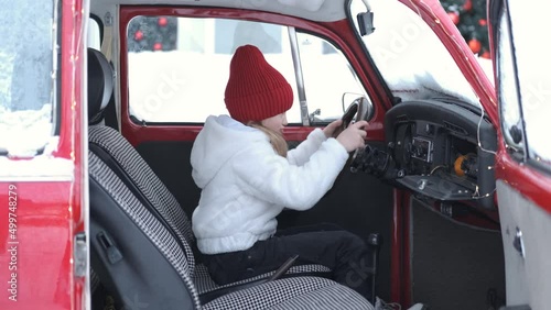 little girl playing driving a car in winter