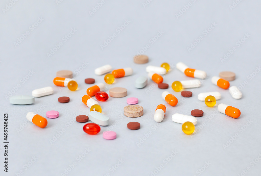 scattered pills and capsules on a gray table close-up scattered pills and capsules on a gray table close-up
