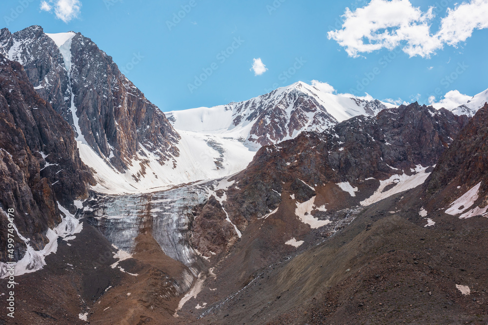 Scenic mountain landscape with vertical glacier and sunlit snow mountains in sunny day. Beautiful alpine view to large glacier with icefall in sunlight. Awesome mountain scenery at very high altitude.