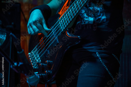 The bass guitarist plays the bass guitar. Dark key. Selective focus photo
