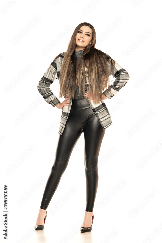 An attractive young woman posing in wool jacket and latex trousers. Fashion look on a white background An attractive young woman posing in wool jacket and latex trousers. Fashion look on a white background