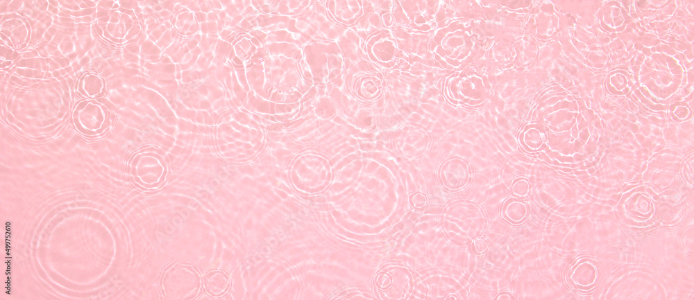 Abstract summer banner background Transparent pink clear water surface texture with ripples, splashes. Water waves in sunlight, copy space, top view. Cosmetics moisturizer micellar toner emulsion