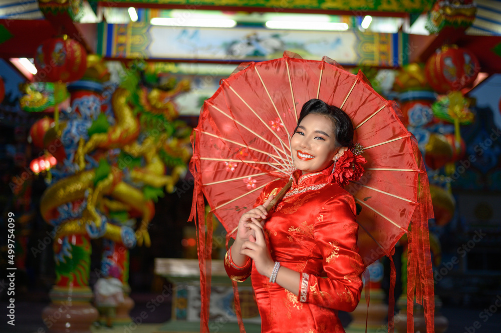 Asian beautiful woman wearing cheongsam with umbrella at shrine on Chinese New Year