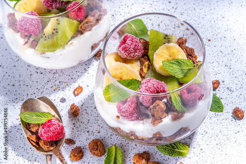 Summer healthy diet breakfast, snack concept. Layered granola breakfast triffle dessert with yogurt and fresh berries and fruits. Two portioned glass with overnight granola oats parfafait dessert photo