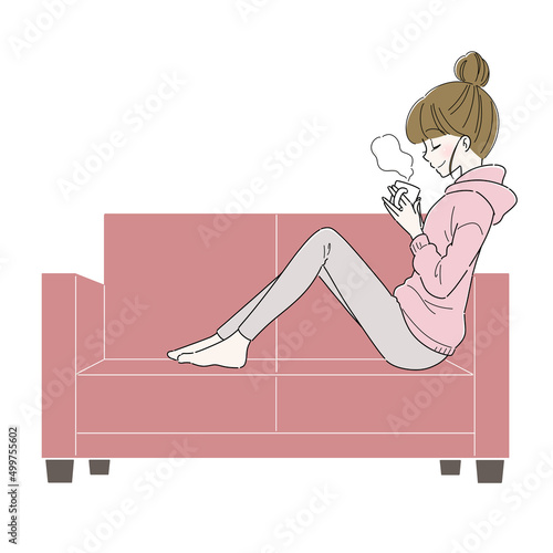 ソファでコーヒーを飲みながらリラックスする女性