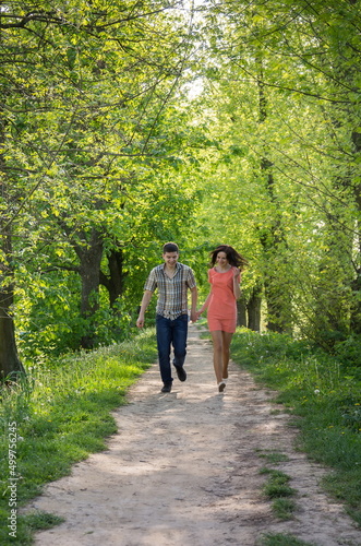 A young couple in love, a guy and a girl, run along the park alley towards them.