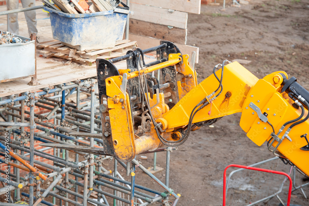 Telehandler on construction site lifting heavy steel box full of ...