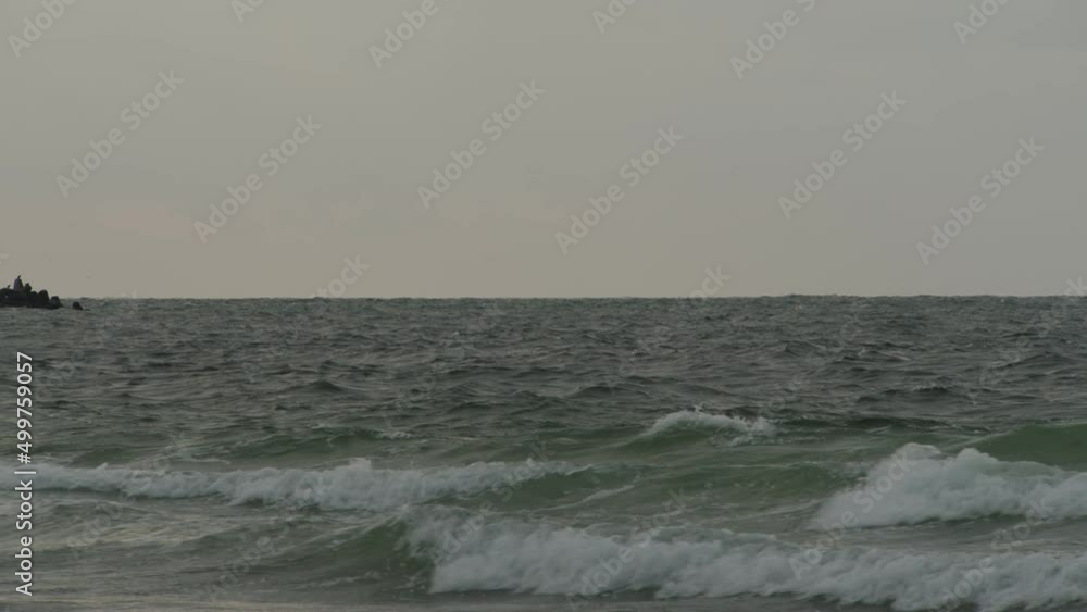 Ocean waves roll towards coastline and crash, dusk time. Static slow motion view Ocean waves roll towards coastline and crash, dusk time. Static slow motion view