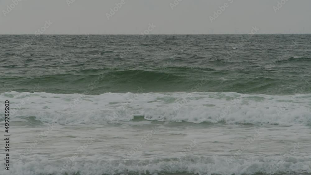 Moody ocean waves rolling towards coastline and crash, static view Moody ocean waves rolling towards coastline and crash, static view