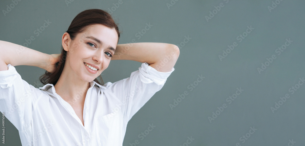 Happy young woman with dark long hair in white shirt on grey background isolated, banner Happy young woman with dark long hair in white shirt on grey background isolated, banner