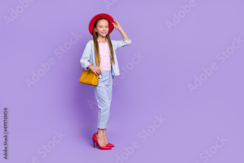 Photo of shiny adorable little school girl wear denim shirt walking mother shoes empty space isolated purple color background