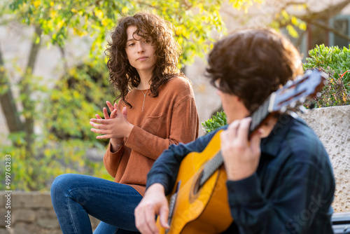 Young curly woman singing with a guitarist man in the street © Marc Calleja