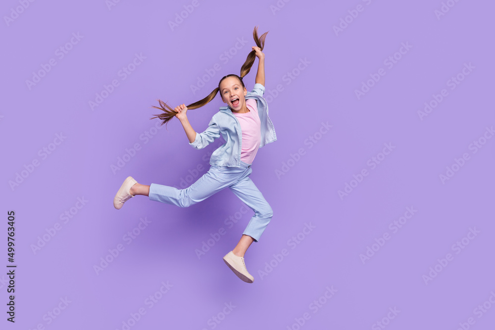 Photo of pretty funky little school girl wear denim shirt jumping high holding tails empty space isolated purple color background