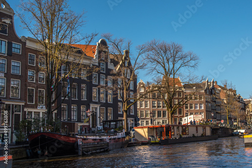 Amsterdam, Netherlands, April 2022. The canals in Amsterdam with the houseboats and the renovated warehouses. photo
