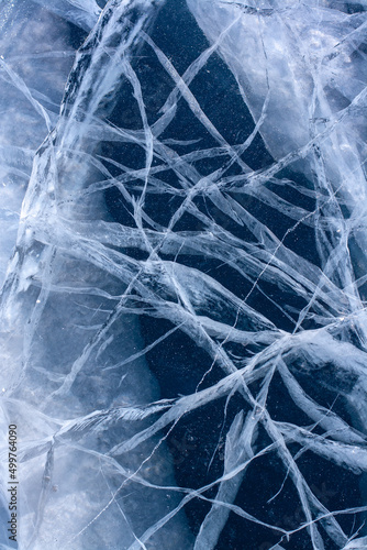 Natural texture of a winter lake. White deep and shallow cracks in transparent clear ice. Blue thick ice. Vertical. © Vladimir Kazakov