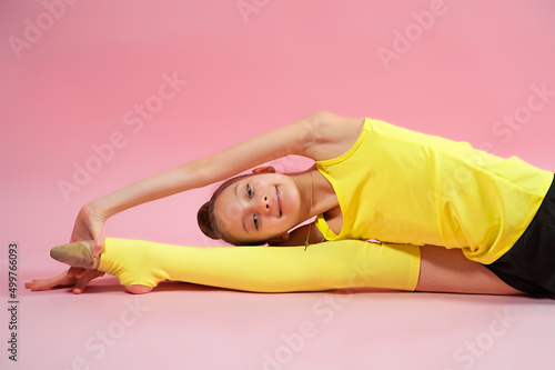 Young gymnast girl stretching and training on a pink background. Sport and healthy lifestyle concept