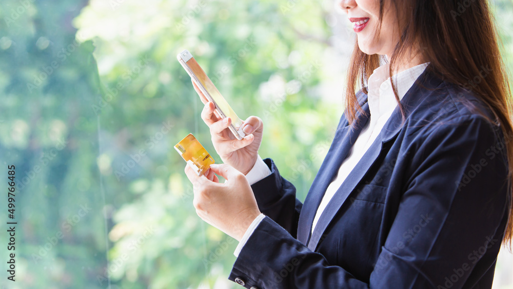 Close Up female hand holding a yellow credit card with smartphone, Online shopping,Order products in the online market Close Up female hand holding a yellow credit card with smartphone, Online shopping,Order products in the online market