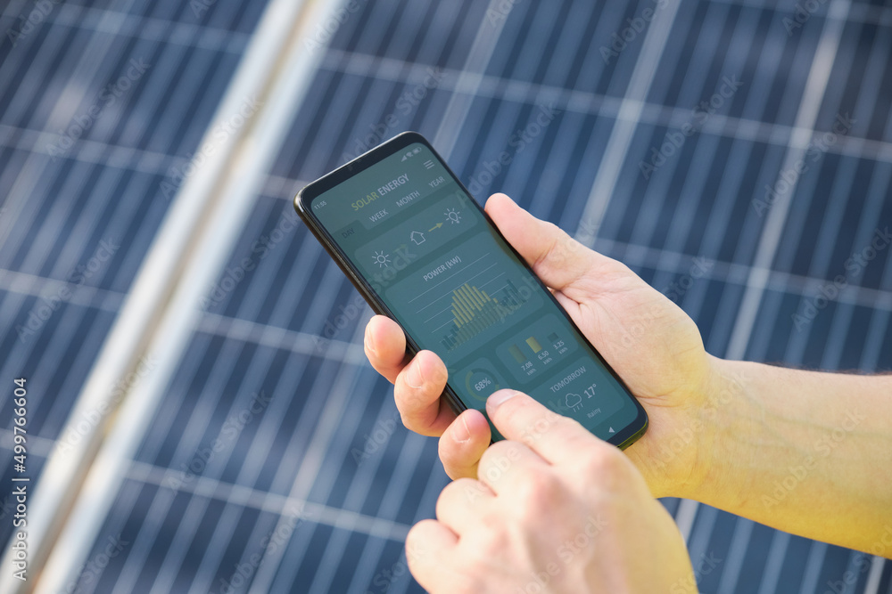 Hands checking solar power generation in a smartphone app. - obrazy, fototapety, plakaty 