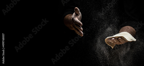 Clap hands of baker with flour. Beautiful and strong men's hands knead the dough make bread, pasta or pizza. Powdery flour flying into air. Long banner format
