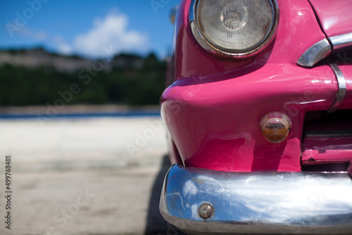 pink old car on a blue background in cuba