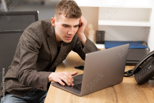 young cheerful programmer working in office on laptop