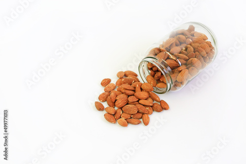 Almonds nuts pour from glass bottle isolated on white background © zilvergolf
