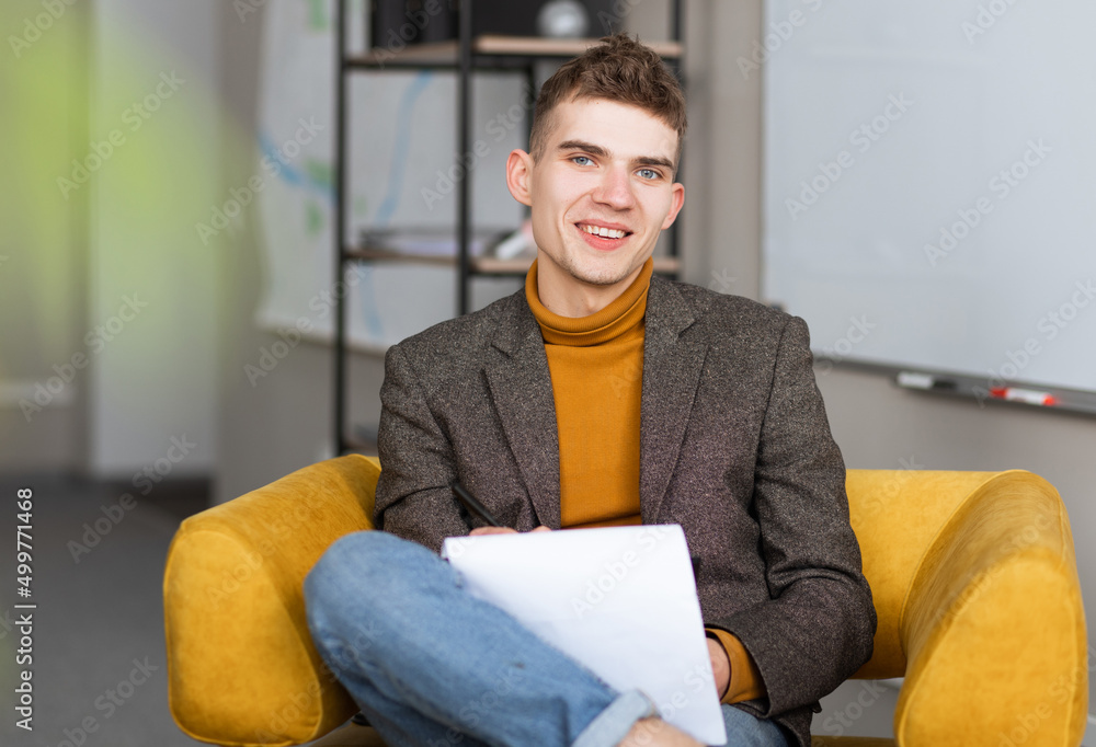 handsome young man smiling at camera and filling out forms