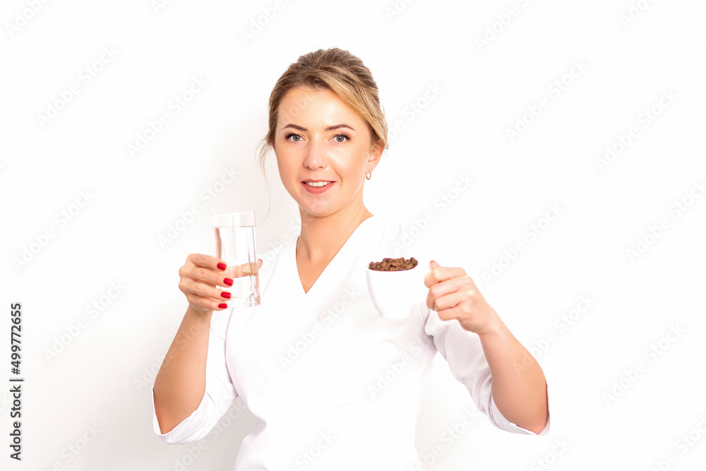 Coffee with water. The female nutritionist holds a cup of coffee beans and a glass of water in her hands on white background Coffee with water. The female nutritionist holds a cup of coffee beans and a glass of water in her hands on white background