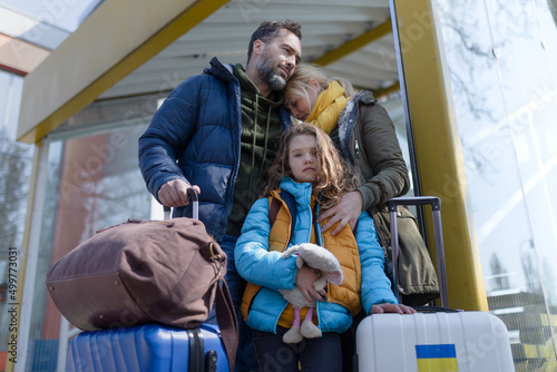 Murais de parede Ukrainian refugee family with luggage at railway station together, Ukrainian war concept