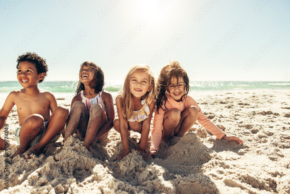 Happy young children playing with beach sand