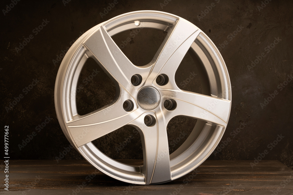 Obraz premium new grey alloy wheels on a dark textured black background. a wheel for a car