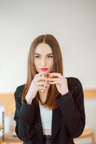 Beautiful, young business woman puts on perfume and enjoys the aroma
