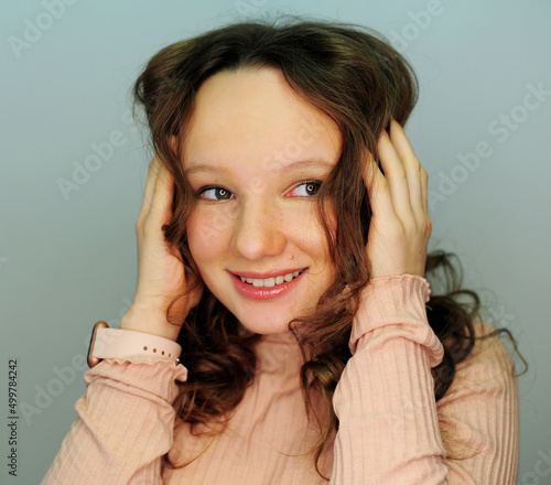 a girl in a make-up studio tinager in pink golf smiles happy with a new makeup in her eyes reflects a lamp for photography gently painted eyelashes and lips hair blonde girl 10-13 years old. photo