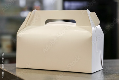 white plain cardboard favor box with handle on concrete table cupcake carrier dessert carrying package blank template