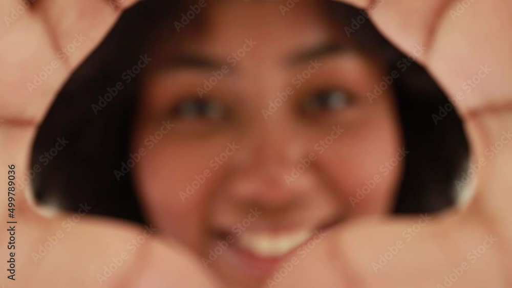 Portrait african american woman puts her hand in a frame and looks at the camera giving you a charming smile. Portrait african american woman puts her hand in a frame and looks at the camera giving you a charming smile.