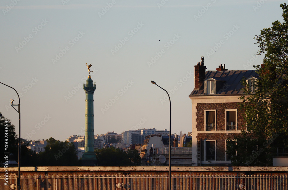 Fototapeta premium View across the Seine to a column in the Place de la Bastille in Paris, at golden hour
