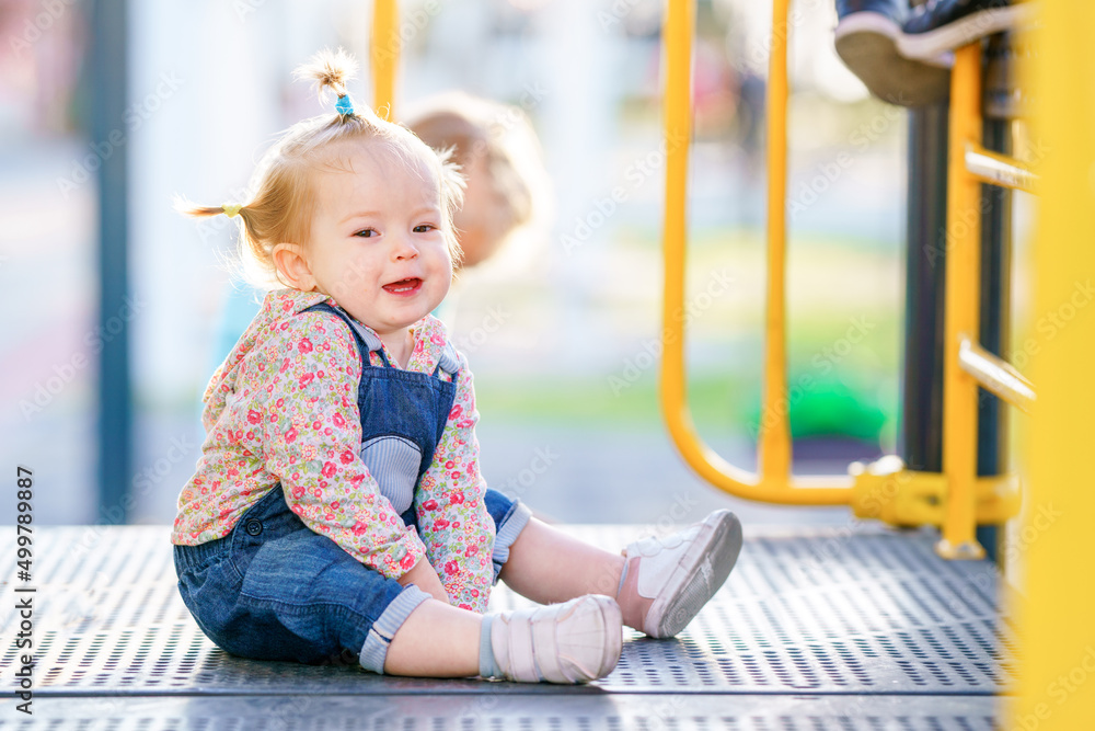 Active games for children. The kid is learning to climb stairs. Funny girl with pigtails on a children's slide. Happy child is playing on the playground. Baby has multi-colored short pigtails Active games for children. The kid is learning to climb stairs. Funny girl with pigtails on a children's slide. Happy child is playing on the playground. Baby has multi-colored short pigtails