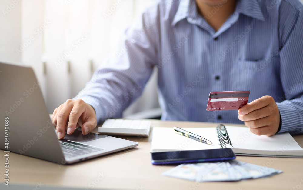 Businessman holding credit card and using laptop. Online shopping ideas and credit card balance check. Businessman holding credit card and using laptop. Online shopping ideas and credit card balance check.