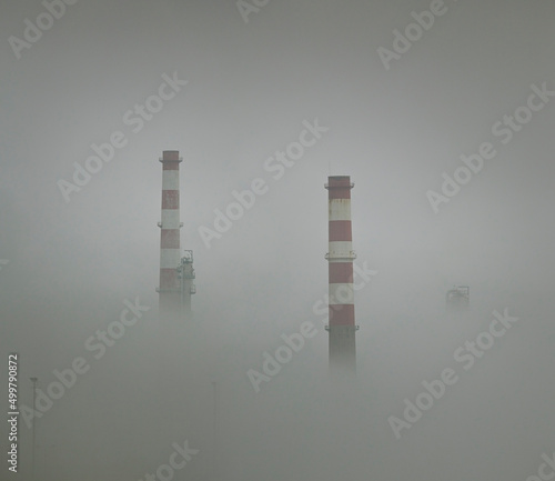 Oil refinery chimeys in the smog photo