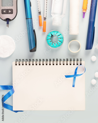 Diabetic composition with glucose meter, test strips for determining blood sugar levels, syringes for insulin injections, sanitizing on a blue background with notebook. Concept of diabetes control