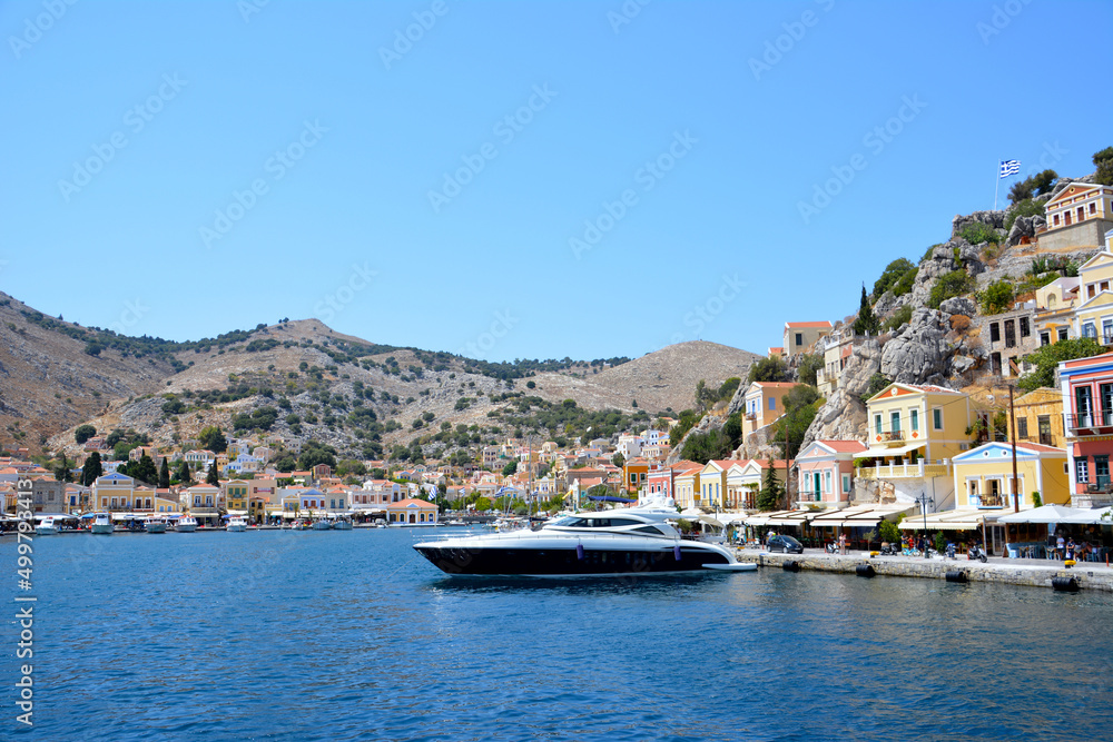boat in seaport of greek island on mountain and coloured houses background