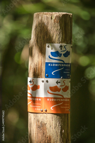 Hattem, The Netherlands, July 31, 2021: wooden pole with little signs indicating Klompenpad (clog path) hiking trails through the forest