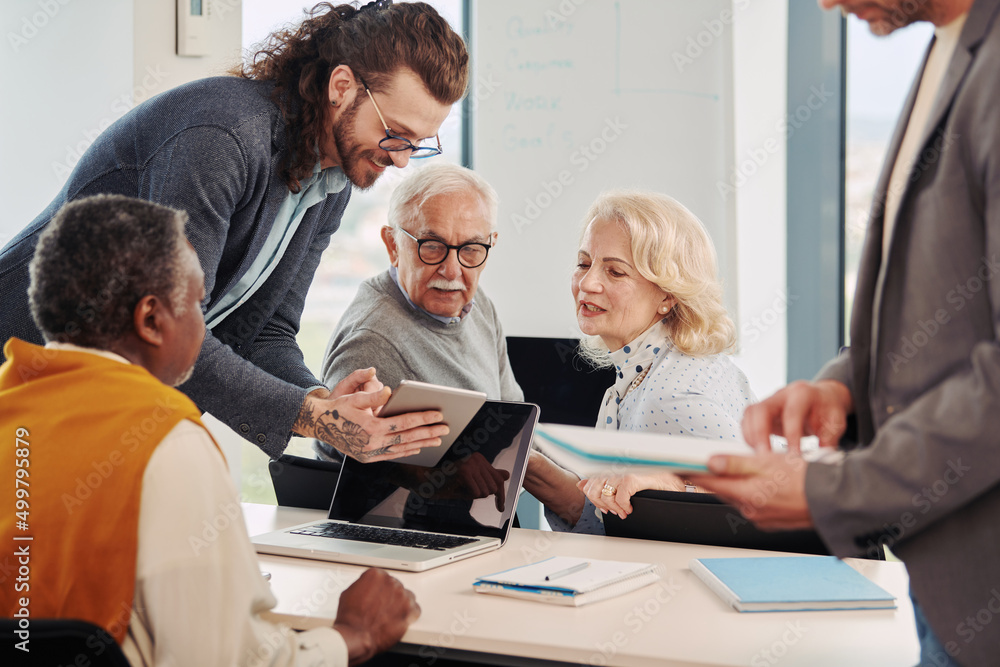A hipster educator teaching a multicultural group of senior students how to use technology and the internet in the classroom. A hipster educator teaching a multicultural group of senior students how to use technology and the internet in the classroom.